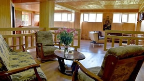 A wooden interior with a round table, chairs, and a bench.