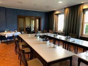 Un salón de conferencias con una larga mesa, sillas y un espejo grande.