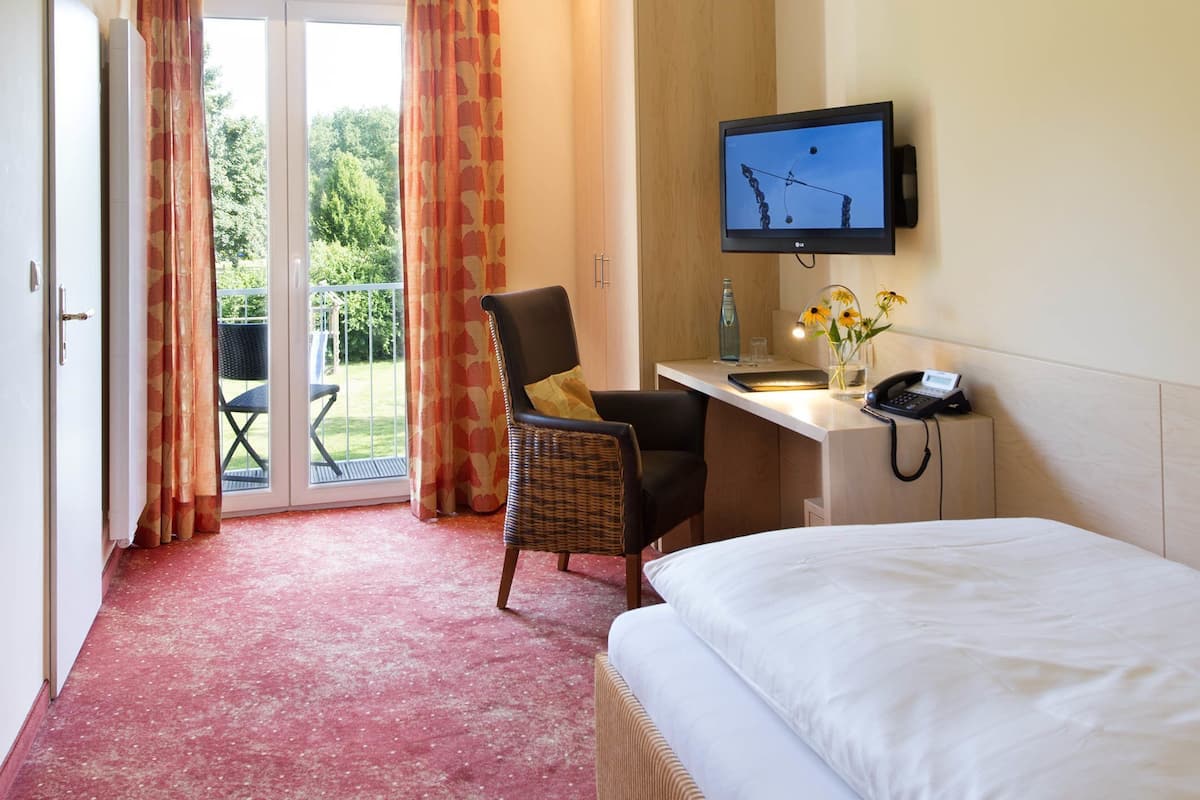 Een hotelkamer met een bed, een bureau met een computer, een stoel, een televisie en uitzicht op het landschap.
