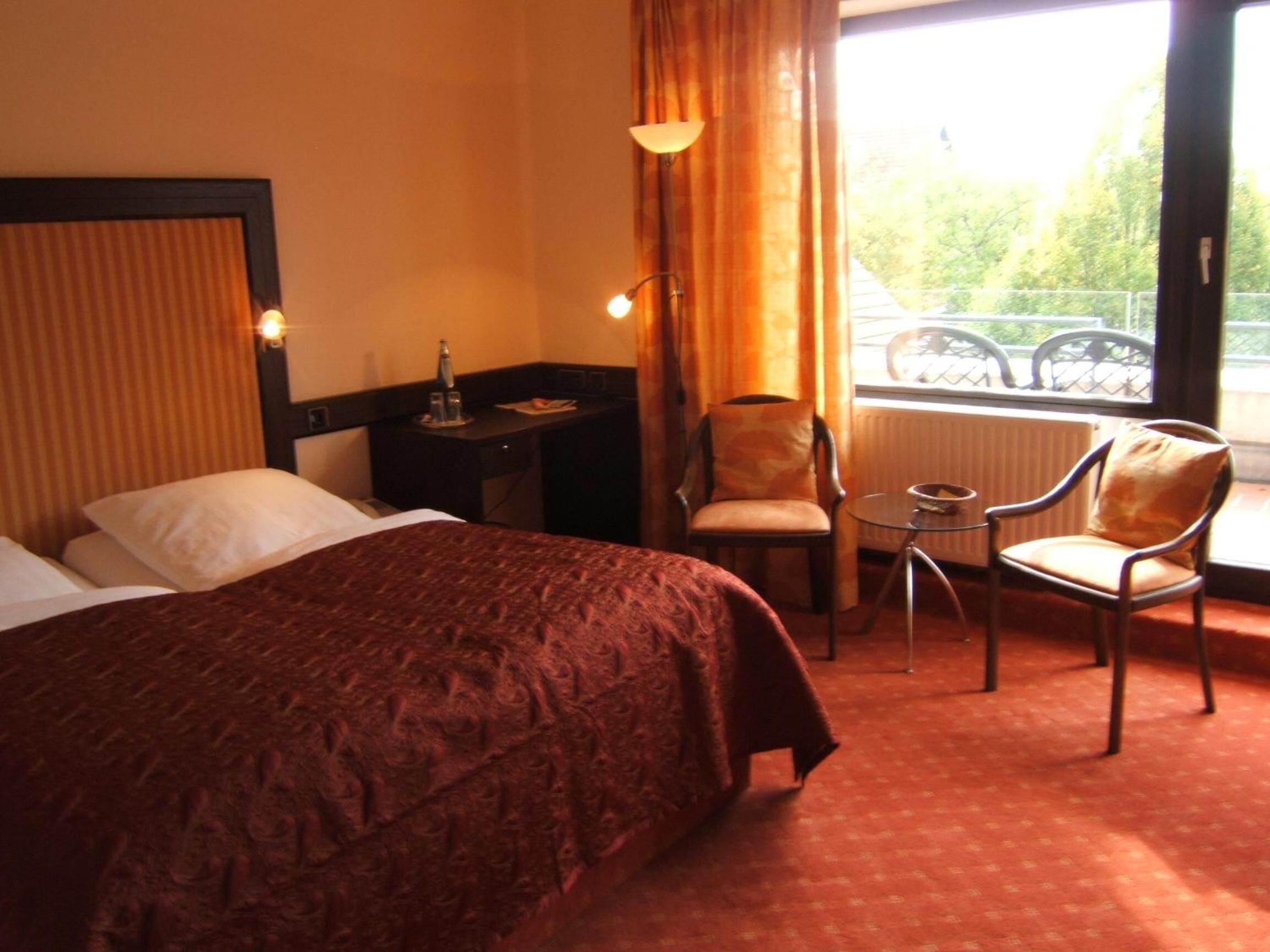 Une chambre d’hôtel avec un grand lit, un bureau, une chaise et une vue sur l’extérieur.