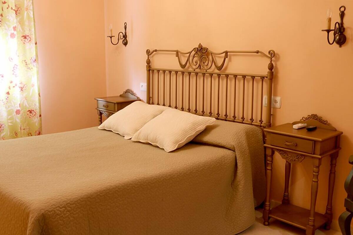 A bed with a wooden headboard, a nightstand with a lamp, and a chair.