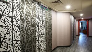 A hallway with a patterned wall, a wooden floor, and a door at the end. - Hua Du Hotel (Keelung)