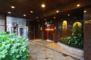 Entrada de un hotel con suelo de baldosas, mostrador de recepción y un cartel con el número 307.