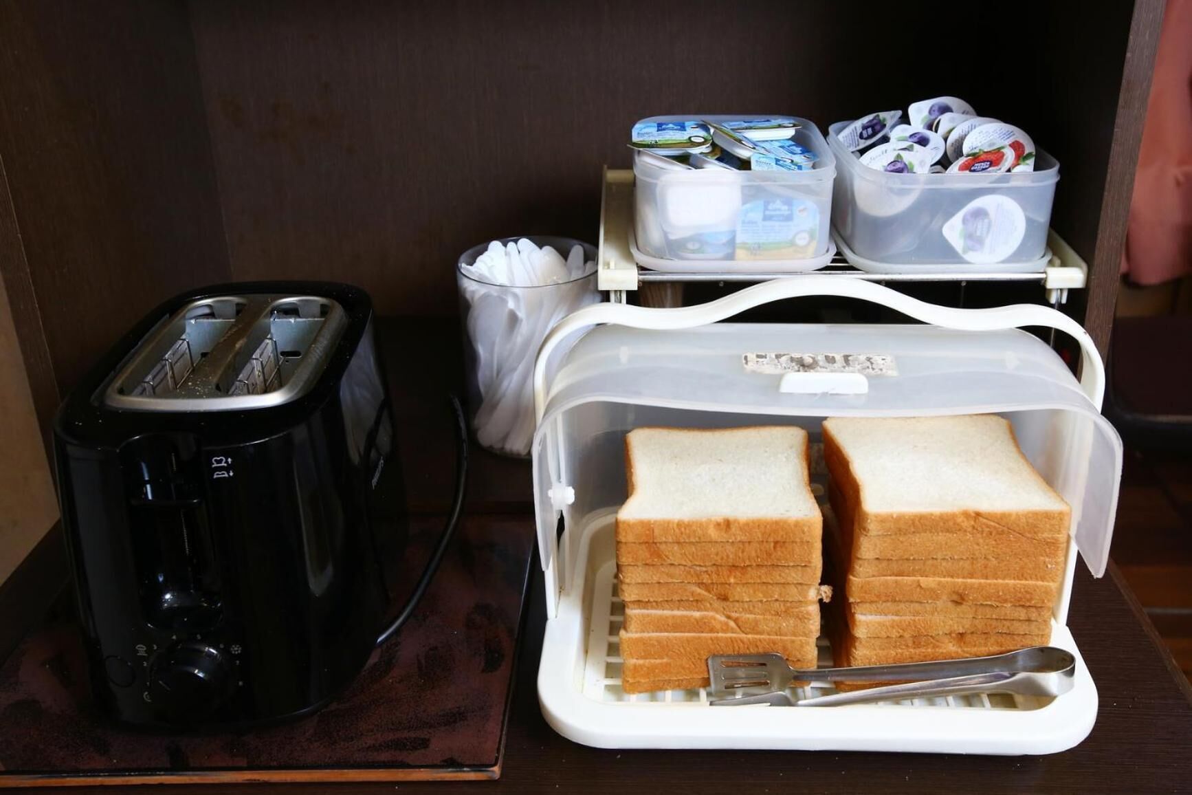 A kitchenette with a toaster, a bread box, and a coffee maker.