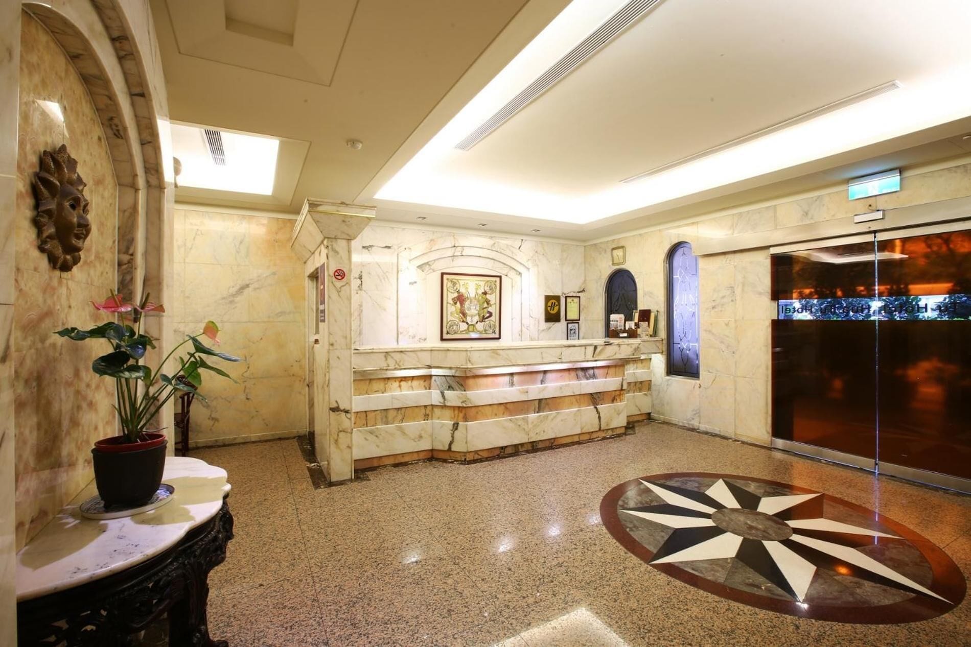 A lobby with a marble reception desk, a staircase, and a large glass door.