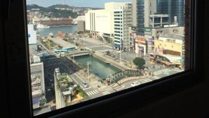 A view from a window of a cityscape with modern buildings, a body of water, and a bridge. - Hua Du Hotel (Keelung)