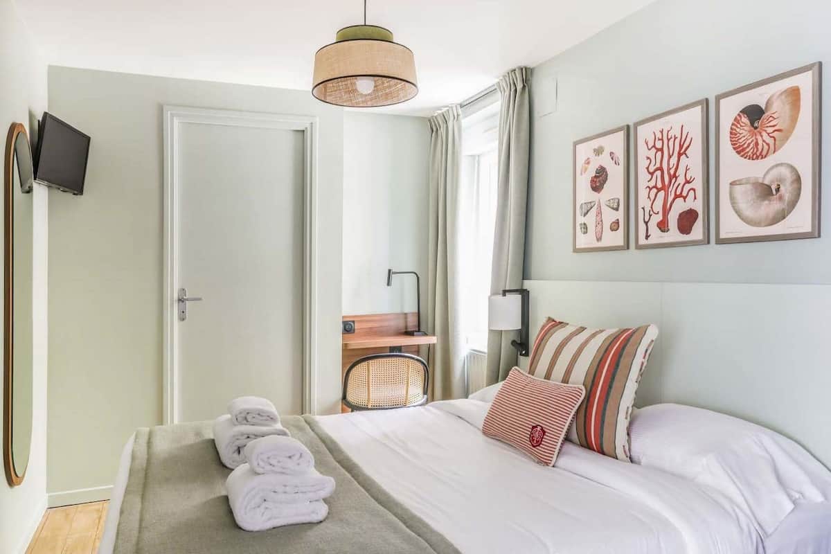 Een hotelkamer met een bed, een stoel, een televisie en kunst aan de muur.
