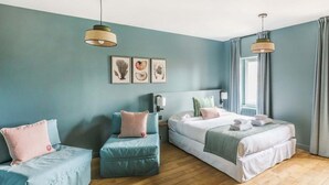 Une chambre avec deux lits, un canapé et une fenêtre avec des rideaux.