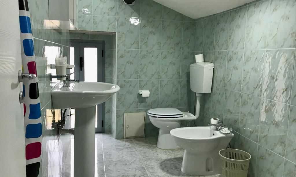 Un bagno con lavandino, WC, bidet e porta carta igienica a parete.