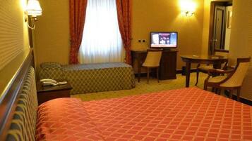 Ein Hotelzimmer mit einem großen Bett, einem Schreibtisch mit Stuhl, einem Fernseher und einem Telefon.