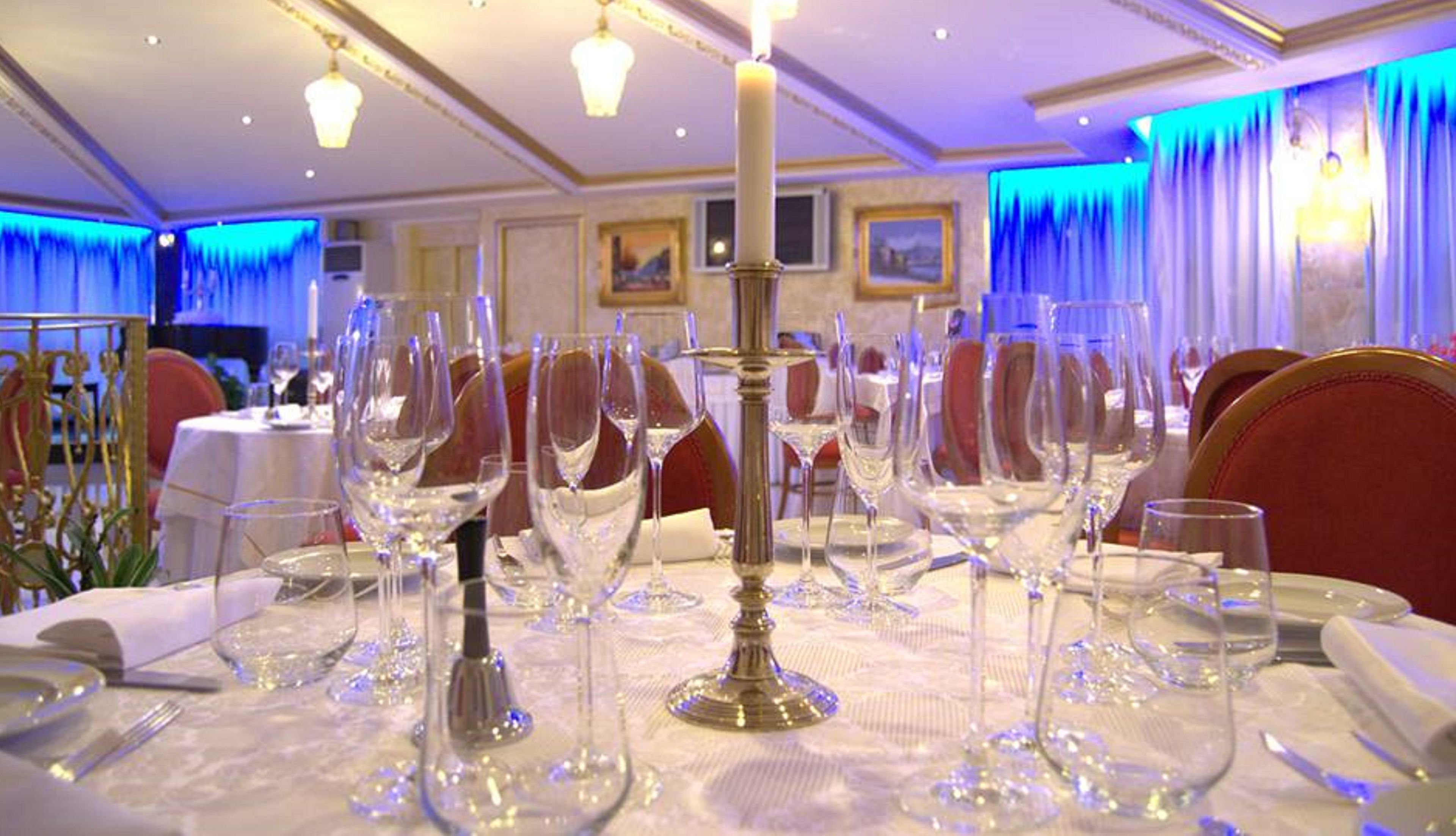 Ein Essbereich mit gedeckten Tischen für ein festliches Mahl, mit klarem Glas und eleganter Tischdekoration.