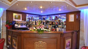 A bar area with a wooden counter, bar stools, and a variety of bottles and glasses. - Hotel Don Carlo 4S (San Marco Argentano)