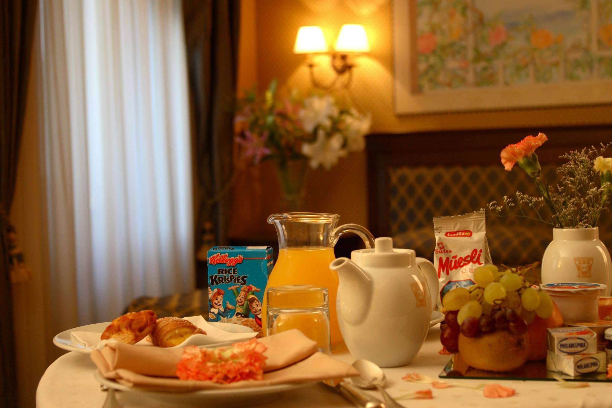 A breakfast table with croissants, cereal, juice, and a pitcher.