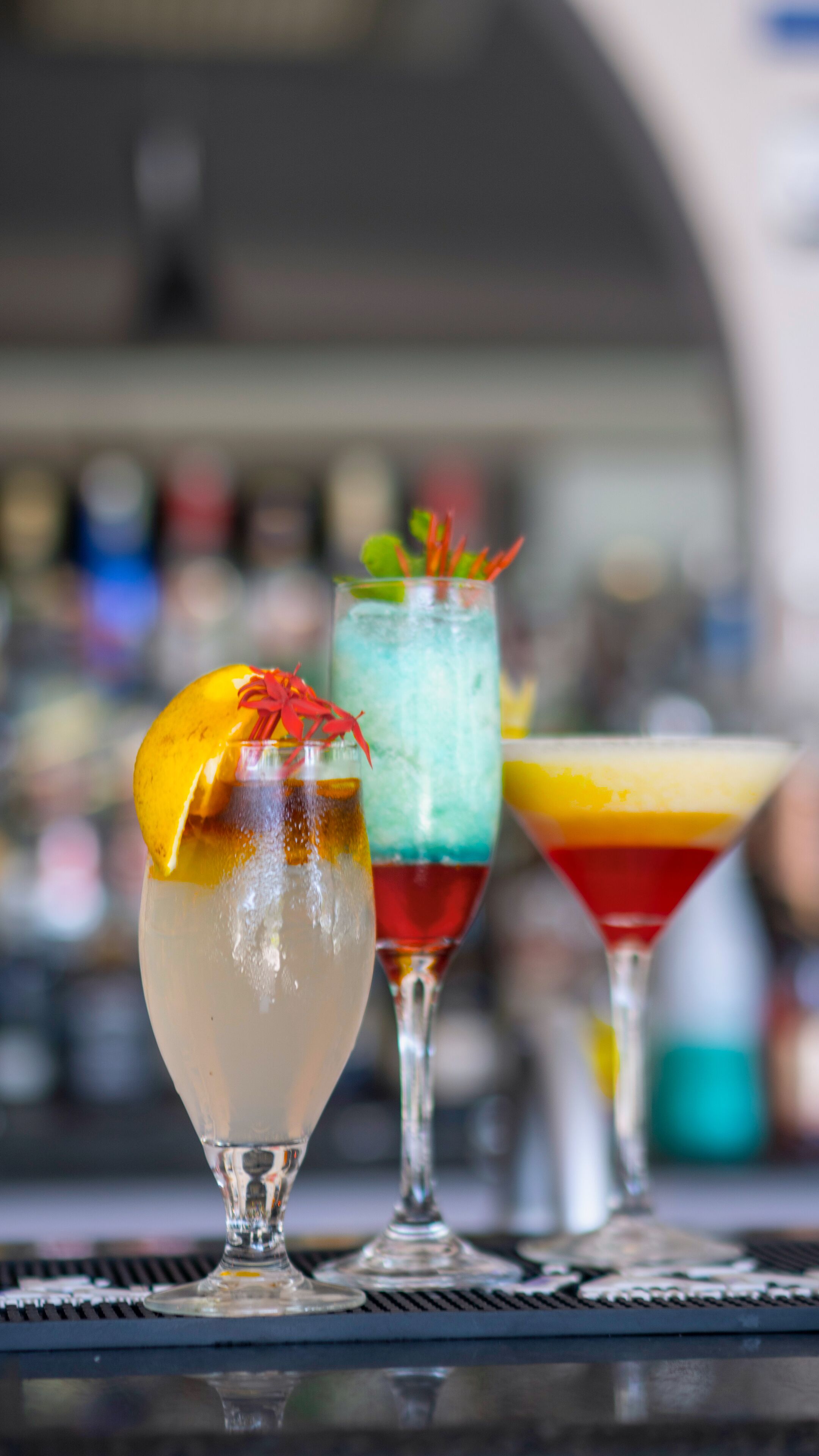 Three cocktails on a bar counter with a blurred background.