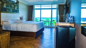 Een hotelkamer met een groot bed, een bureau met een koelkast en uitzicht op het omliggende landschap.