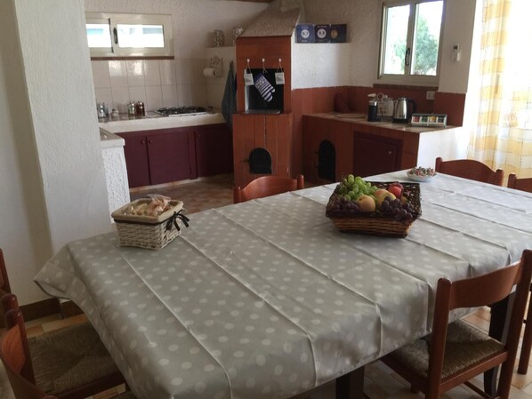 A dining area with a table set for two, a basket of fruit, and a basket of bread on the table. - B&B Villa Prisiclla (Cinisi)