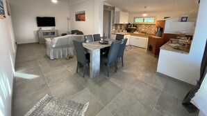 A modern living space with a dining area, kitchen, and a TV mounted on the wall.