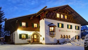 A traditional Alpine-style building with a wooden facade, a balcony with flower boxes, and a sign indicating it is a hotel. - Hotel Garni Zugspitz (Farchant)