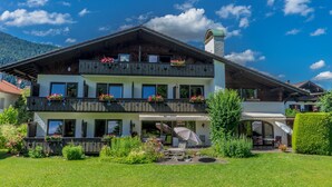 A two-story building with balconies, outdoor seating, and a garden. - Hotel Garni Zugspitz (Farchant)