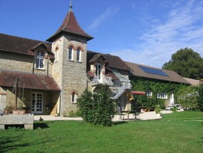 A stone building with a tower, a balcony, and a covered patio area. - Chambres d'hôtes Le Relais de la Perle (Le Vernois)