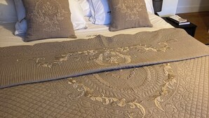A neatly made bed with a brown headboard, white and brown pillows, and a quilted bedspread.