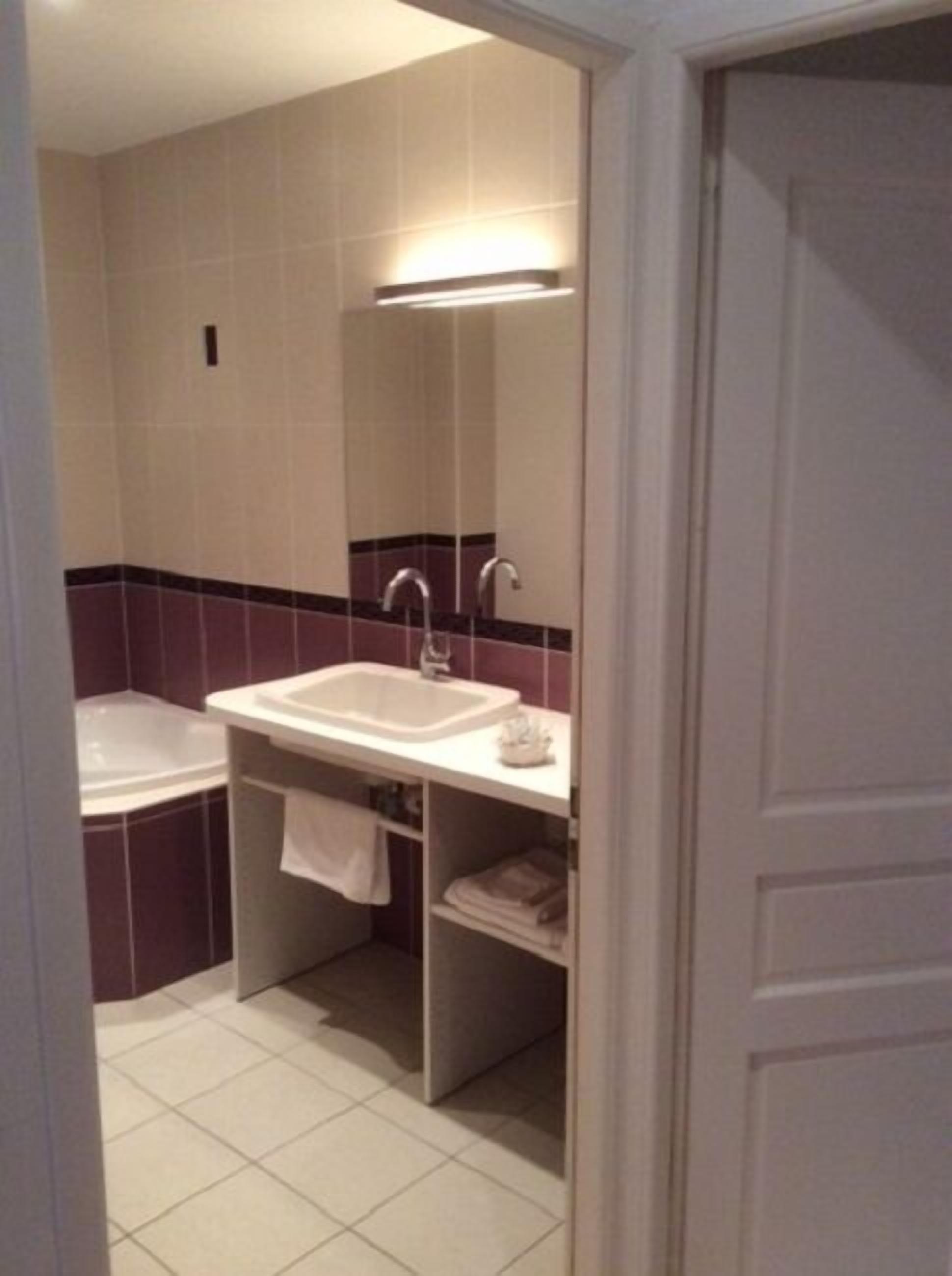 Een badkamer met een wastafel, spiegel en bad.