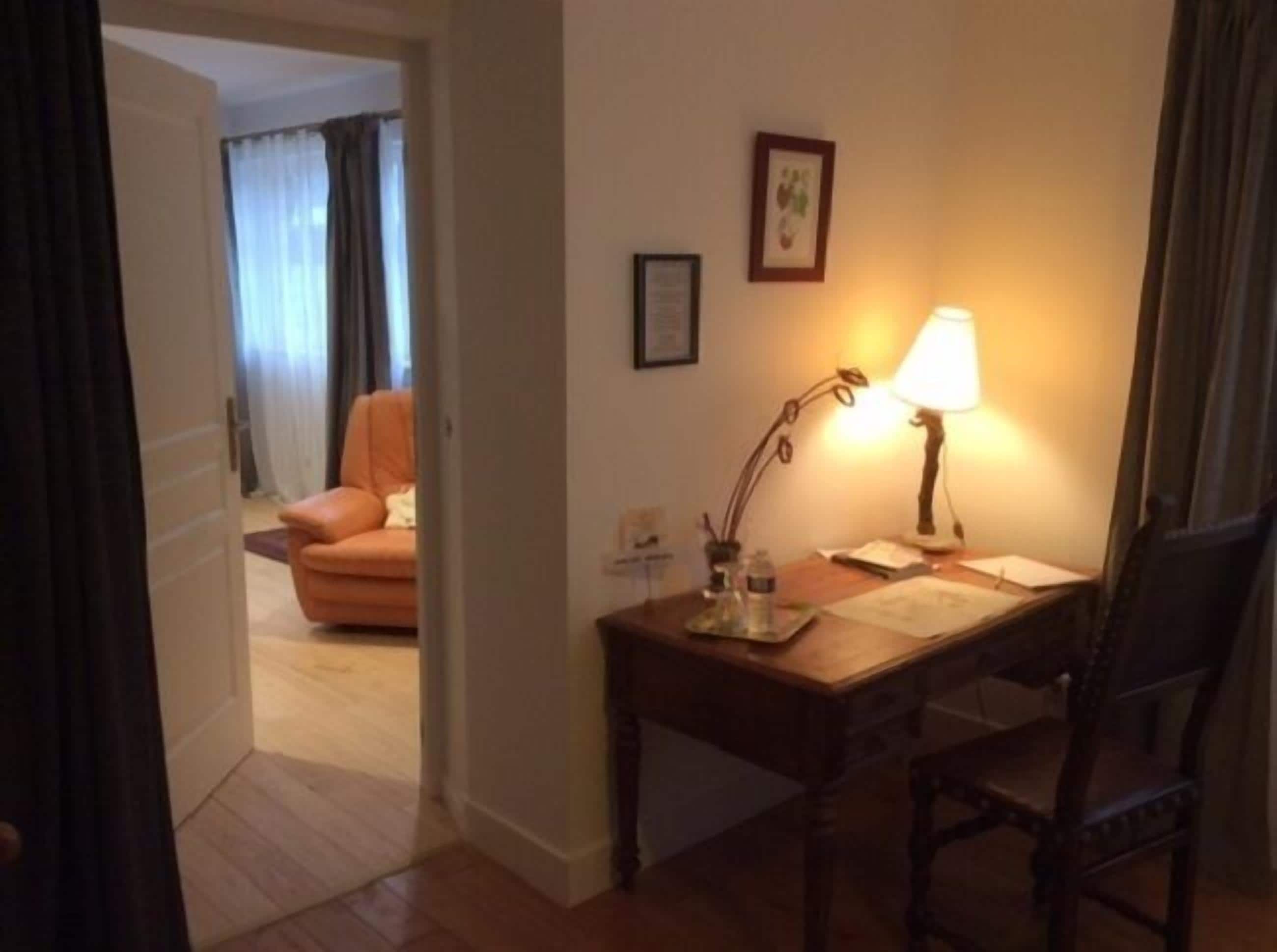 Une chambre d’hôtel avec un bureau en bois, une chaise, une lampe et un tableau encadré au mur.