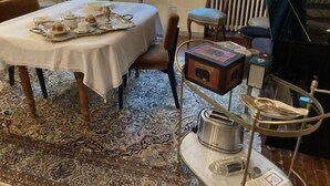 A dining area with a table set for tea, a vintage radio, and a radiator in the background.
