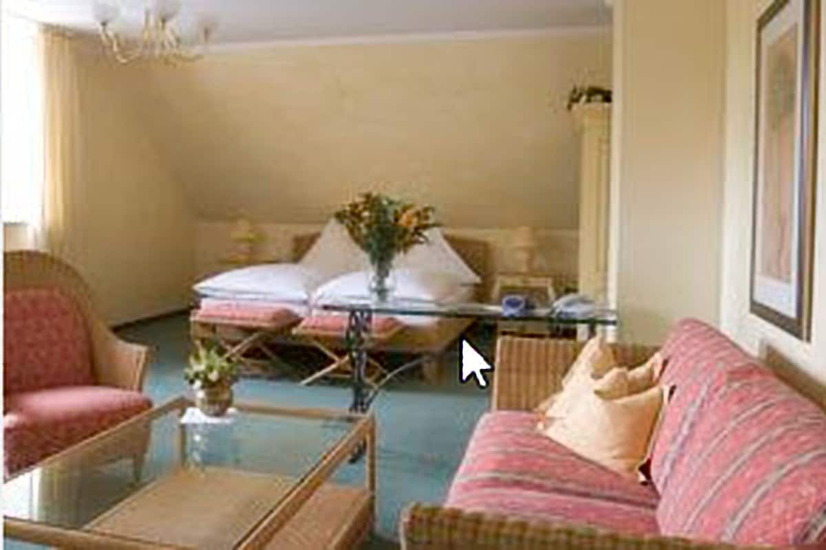 Un salon avec un canapé, des fauteuils, une table basse et un téléviseur.