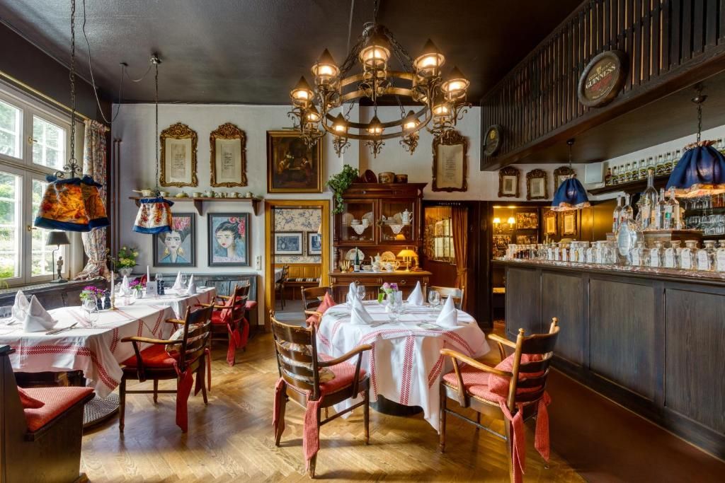 En restaurantindretning med træborde, stole og en bar med flasker.