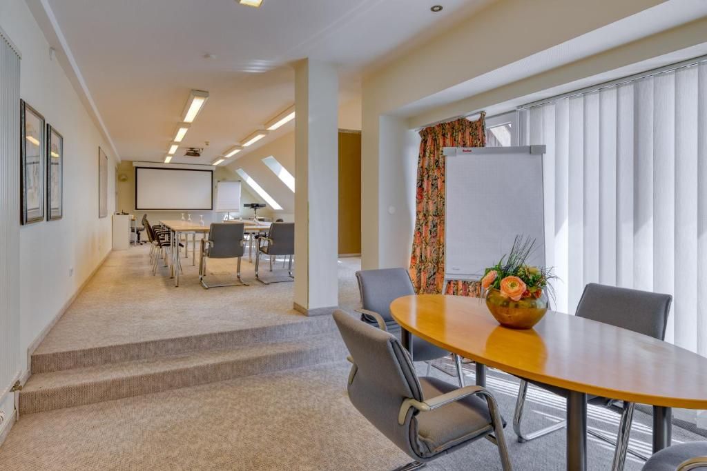 A conference room with a large table, chairs, a projector screen, and a whiteboard.