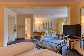 A hotel room with a bed, a television, a desk, and a seating area with a sofa and armchairs. - Hotel Restaurant Alt Vellern (Beckum)