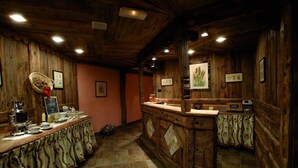 Un interior rústico de madera con una larga barra, cuadros enmarcados y piso de baldosas.