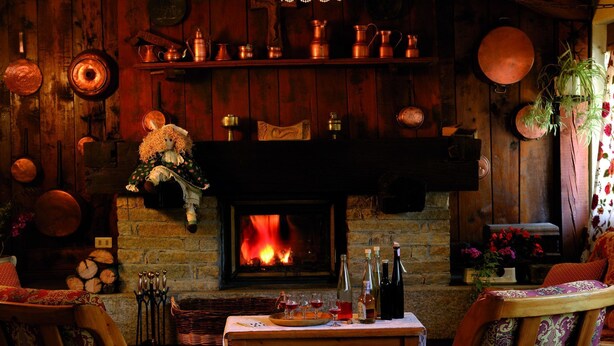 Una habitación acogedora con chimenea, paredes de madera y una mesa con copas y botellas de vino.