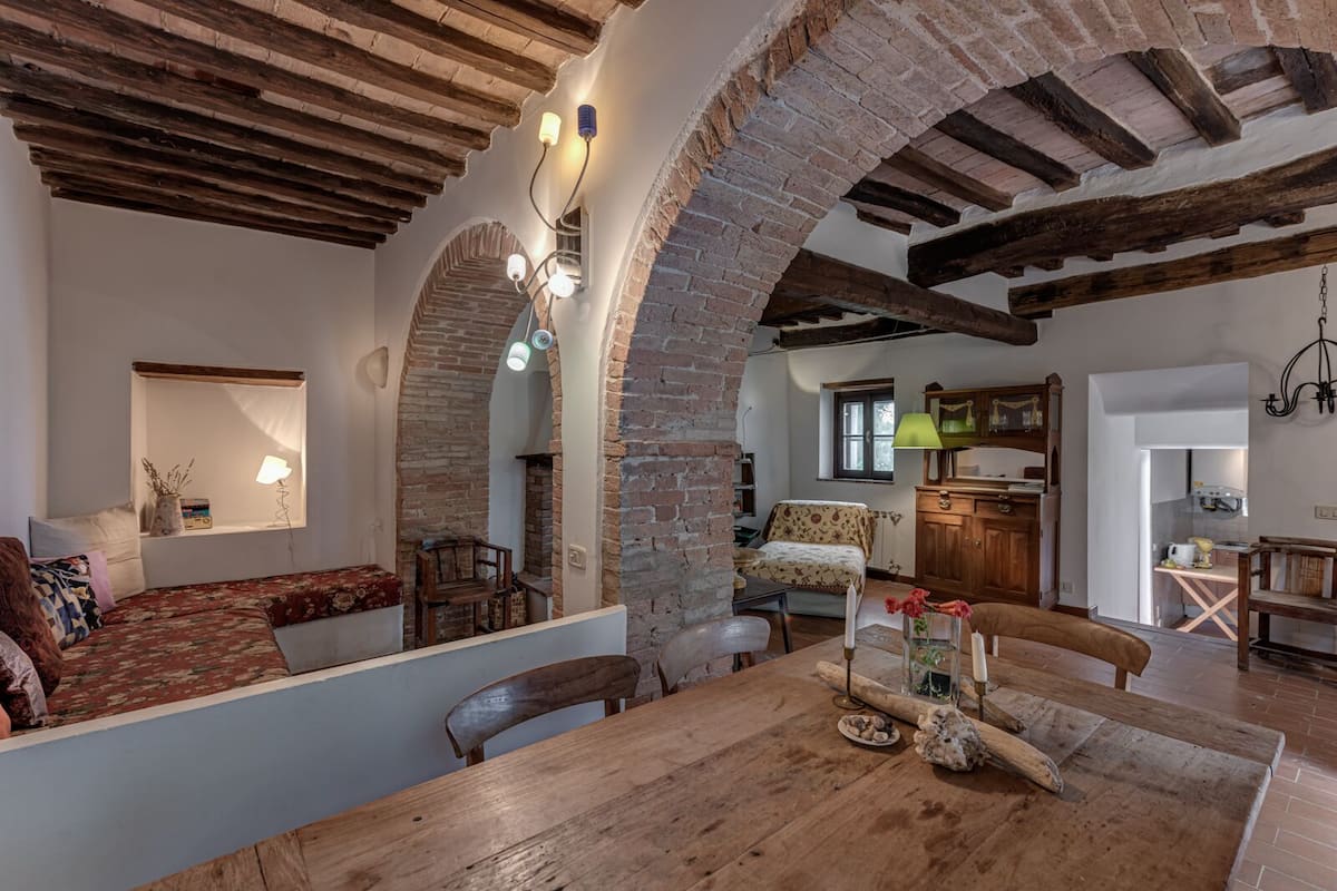 A rustic interior with exposed brick arches, a wooden dining table, and a cozy seating area.