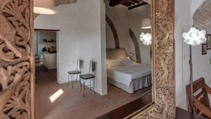 Una camera da letto con un letto, due sedie e uno specchio con decorazioni elaborate.