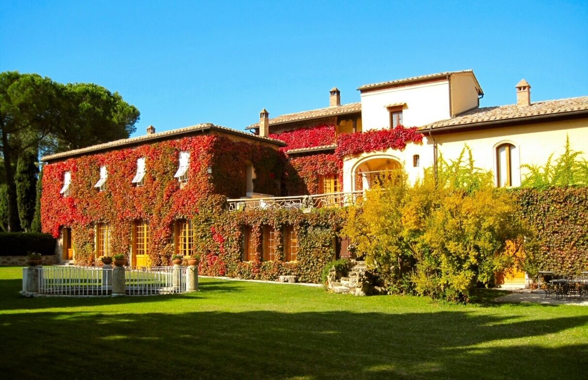 A building with a garden in front, featuring a white fence and a clear sky.