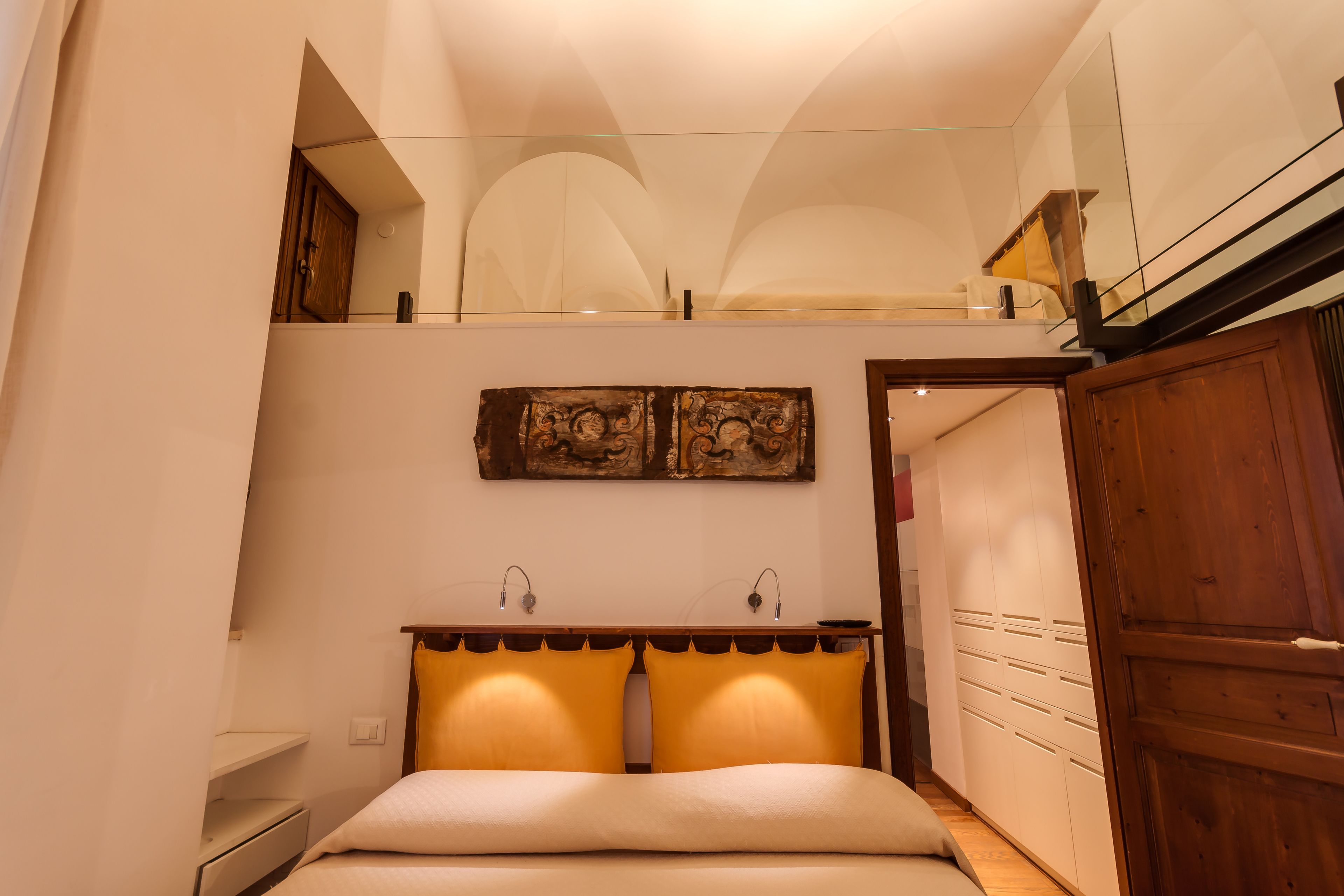 A bedroom with a bed, bedside tables, a mirror, and a wardrobe.