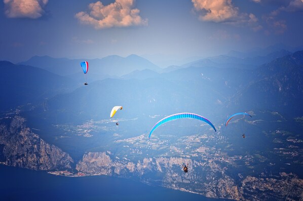 A mountainous landscape with multiple paragliders. - O-live Agriresort (Arco)