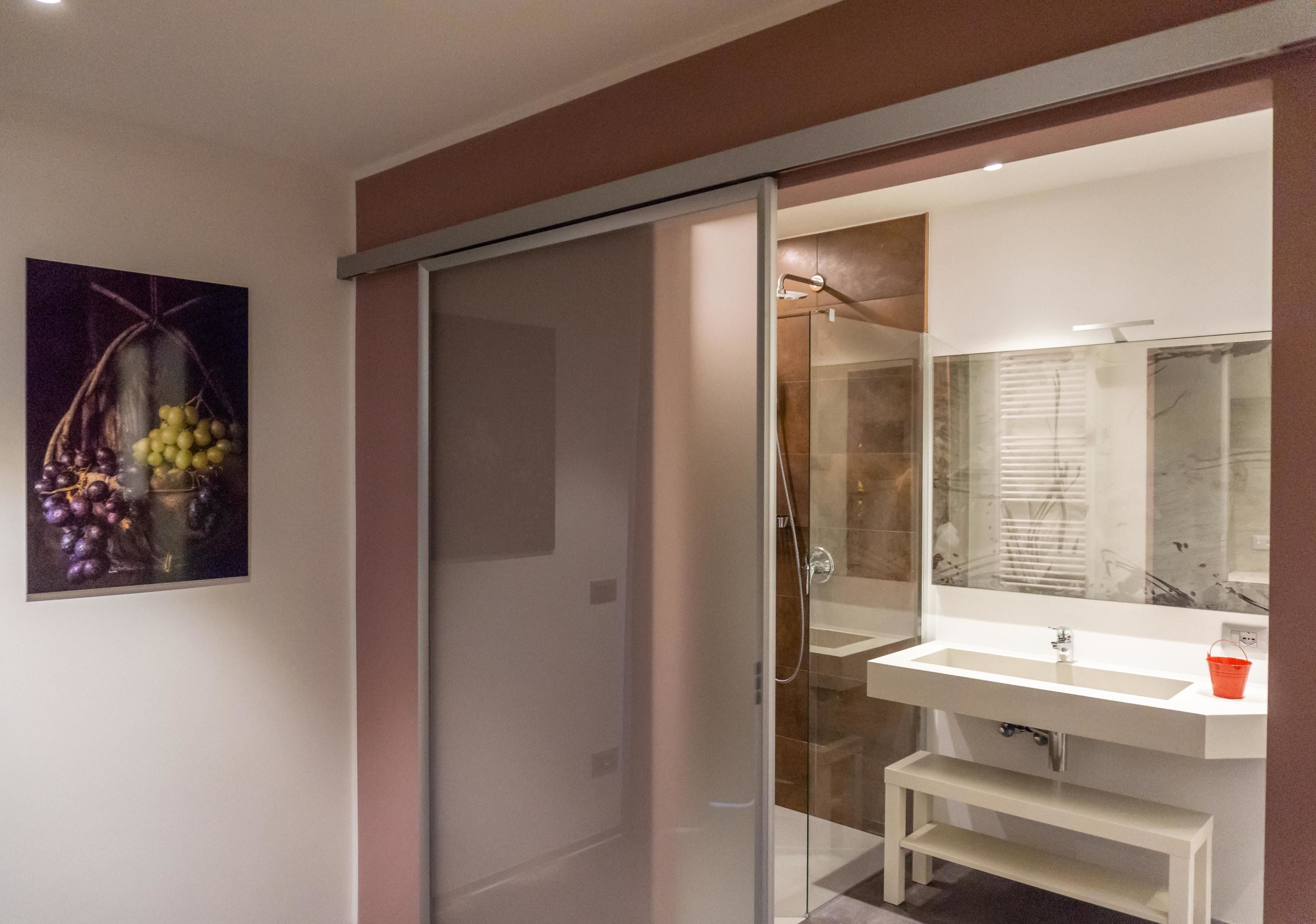 Un bany modern amb una cabina de dutxa de vidre, un lavabo blanc i un mirall gran.