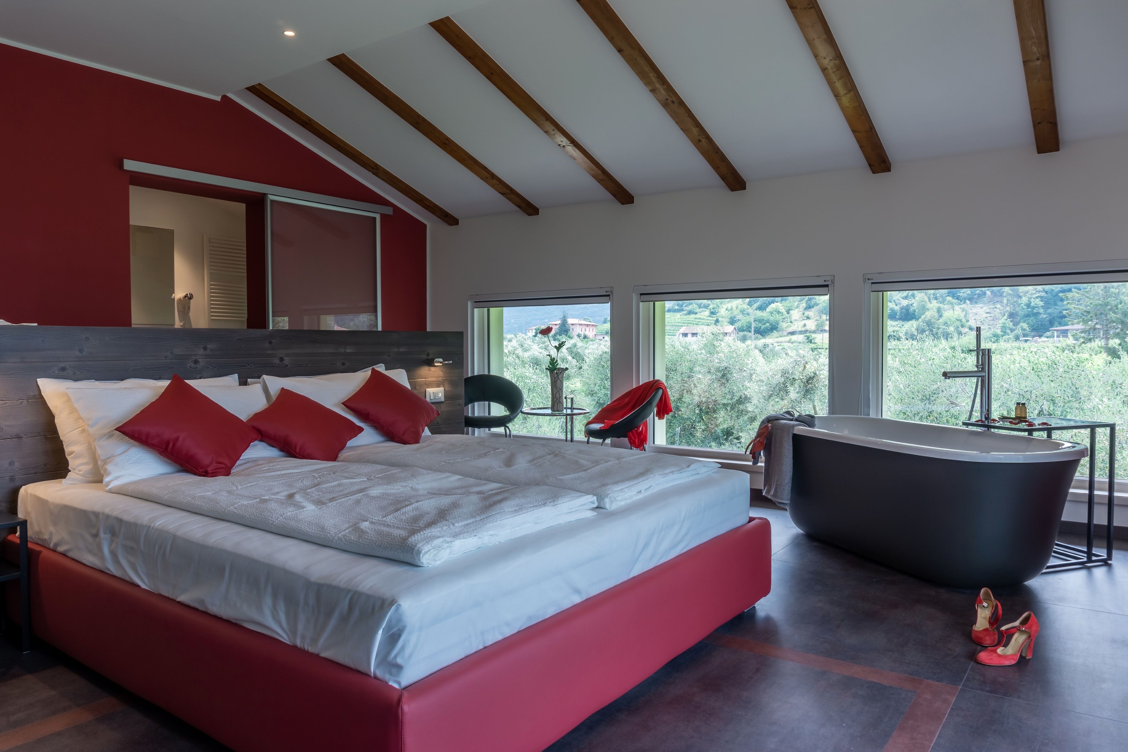 Un dormitorio moderno con una cama grande, una bañera y vistas a zonas verdes.