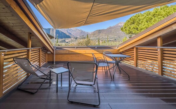 Una terraza de madera con una mesa y sillas, con vistas a un paisaje montañoso.