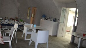 A dining area with a table and chairs, a kitchen counter, and a door leading to another room. - Casa Torre Allera (Cuneo)