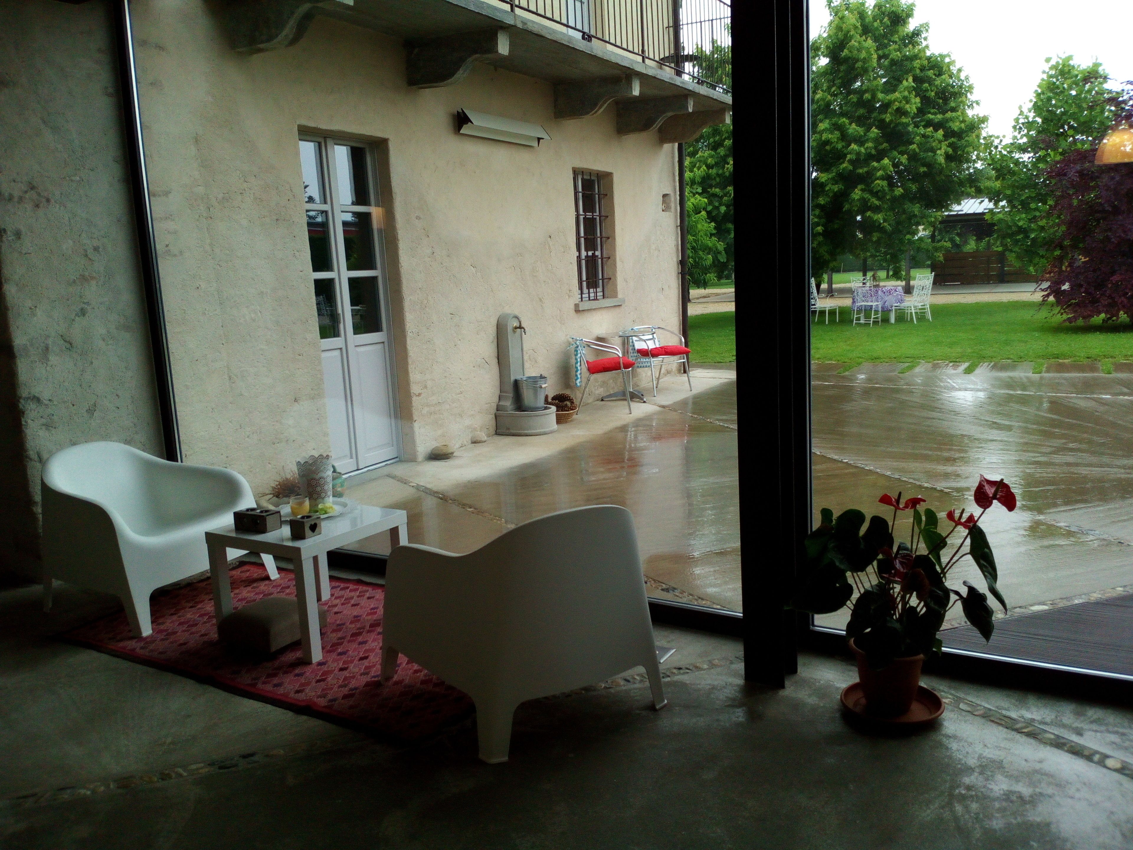 Ein Zimmer mit Betonboden, einem weißen Stuhl, einem kleinen Tisch und einer Topfpflanze.