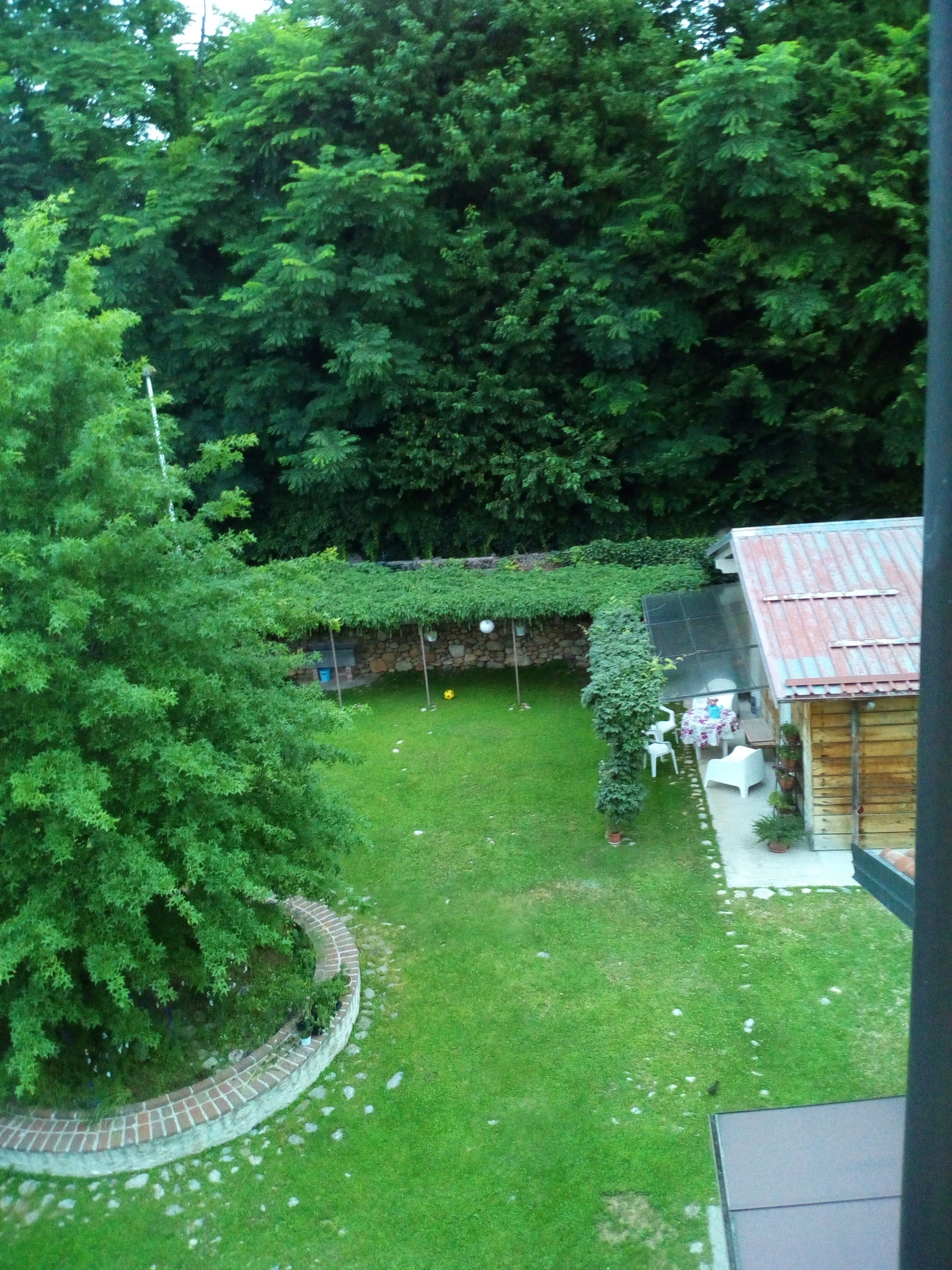 On peut admirer un jardin luxuriant et verdoyant, avec un mur de pierre, un abri en bois et un chemin pavé de briques.
