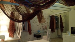 A bedroom with a bed, a bedside table, a TV, a dresser, and a small table with a candelabra. - Casa Torre Allera (Cuneo)