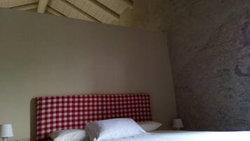 Una camera da letto con una testiera a quadri, un letto con lenzuola bianche, un comodino con una lampada e un muro con motivo decorativo.