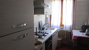 Een compacte keuken met een gasfornuis, gootsteen en een klein eethoekje met tafel en stoelen.
