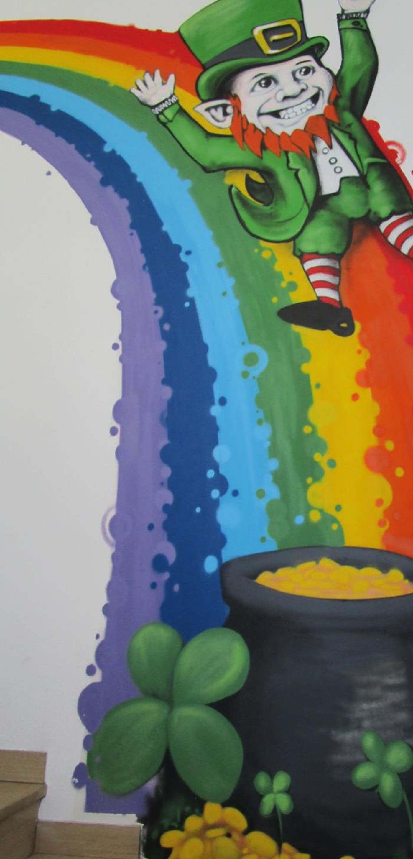A leprechaun painting with a rainbow and a pot of gold.