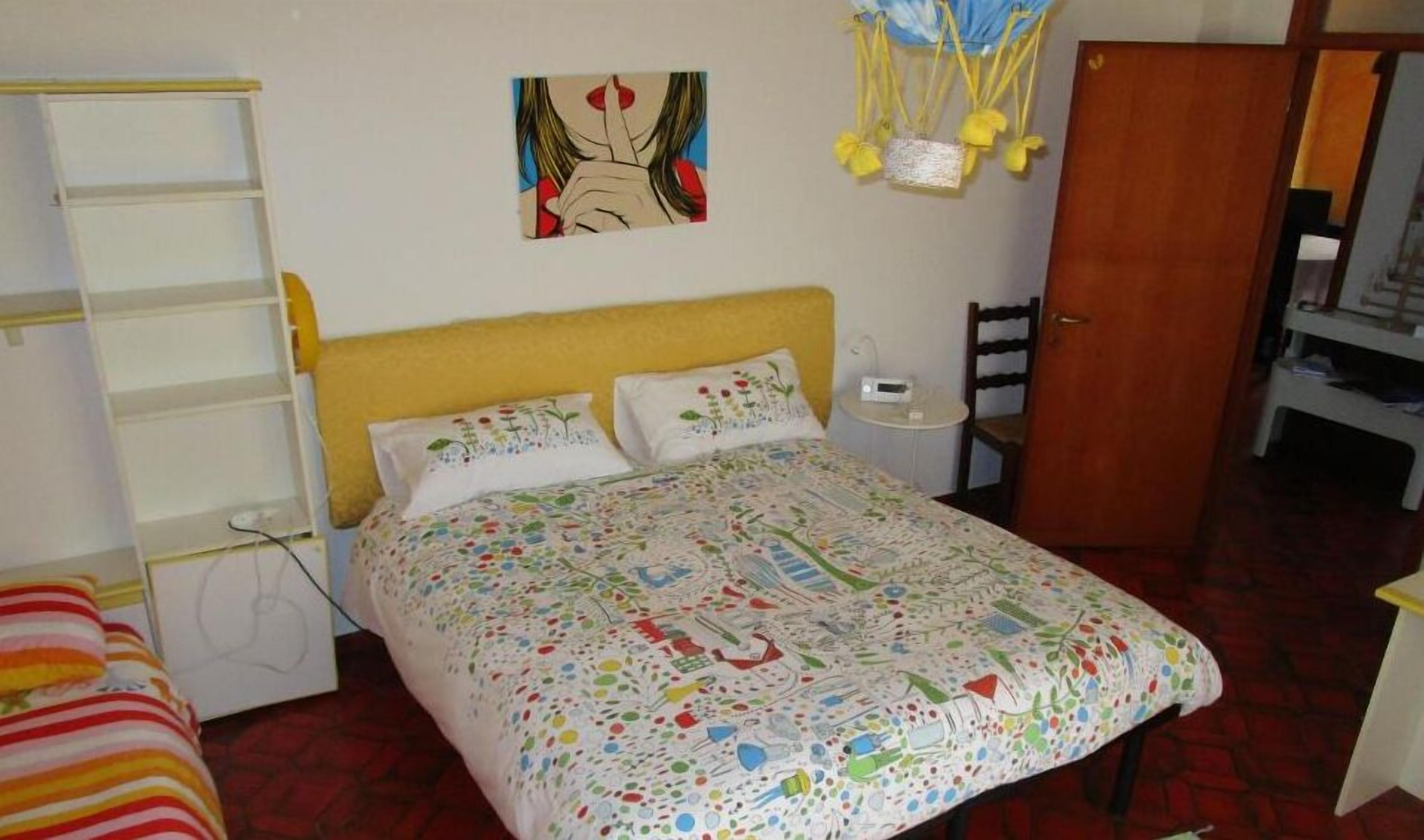Quarto com cama, mesa de cabeceira, cadeira, guarda-roupa e um quadro na parede.